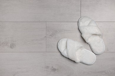 Photo of Pair of soft slippers on wooden floor, top view. Space for text