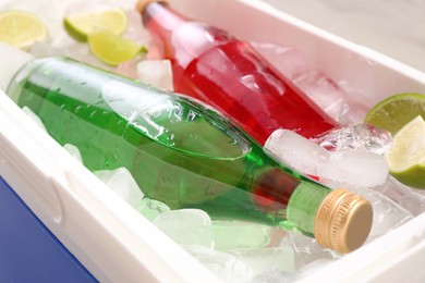 Plastic cool box with ice cubes and refreshing drinks, closeup