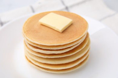 Delicious pancakes with butter on table, closeup