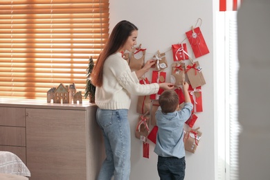 Mother and son taking gift from Advent calendar at home, back view. Christmas tradition