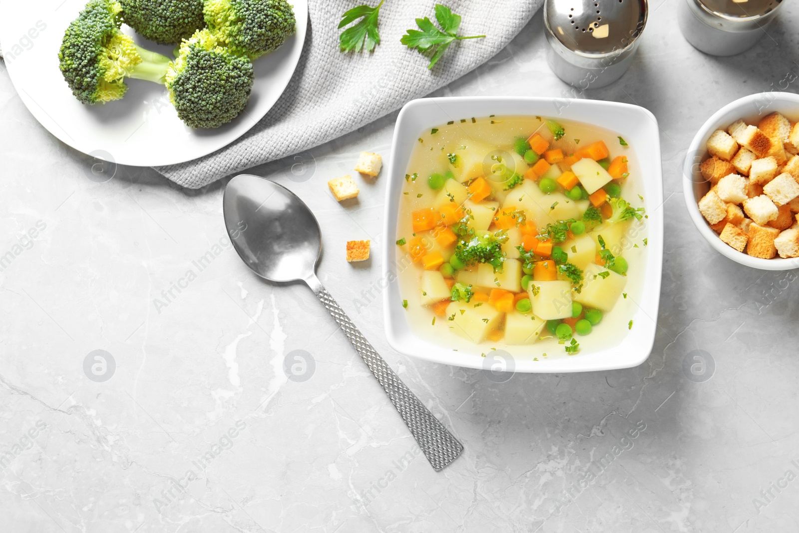 Photo of Bowl of fresh homemade vegetable soup served on grey marble table, flat lay, Space for text