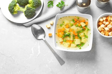 Bowl of fresh homemade vegetable soup served on grey marble table, flat lay, Space for text