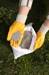 Photo of Woman with fertilizer on green grass outdoors, top view