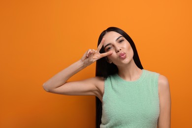 Photo of Beautiful young woman blowing kiss on orange background. Space for text