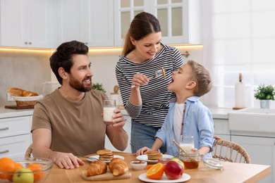 Happy family having breakfast at table in kitchen