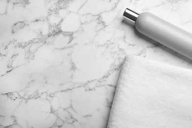 Photo of Towel and shampoo on marble background, top view with space for text