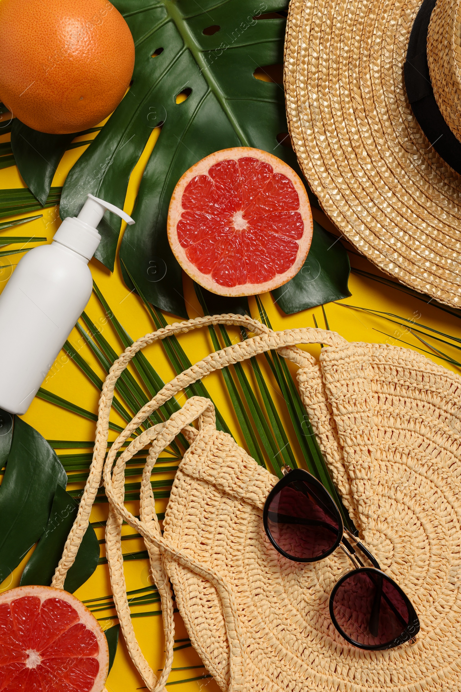 Photo of Flat lay composition with beach bag and green leaves on orange background