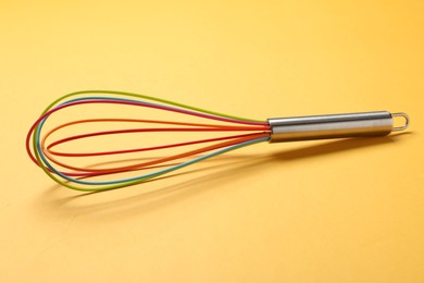 Bright whisk on yellow background. Kitchen tool