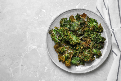 Tasty baked kale chips on light grey marble table, top view. Space for text