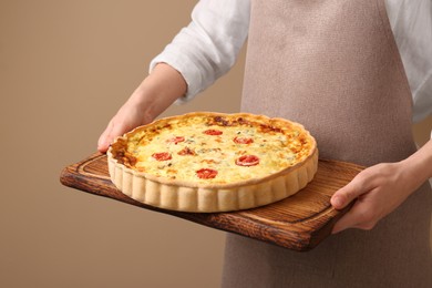 Photo of Woman with delicious homemade cheese quiche on beige background, closeup