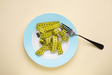 Photo of Measuring tape and fork on beige background, top view. Weight loss concept