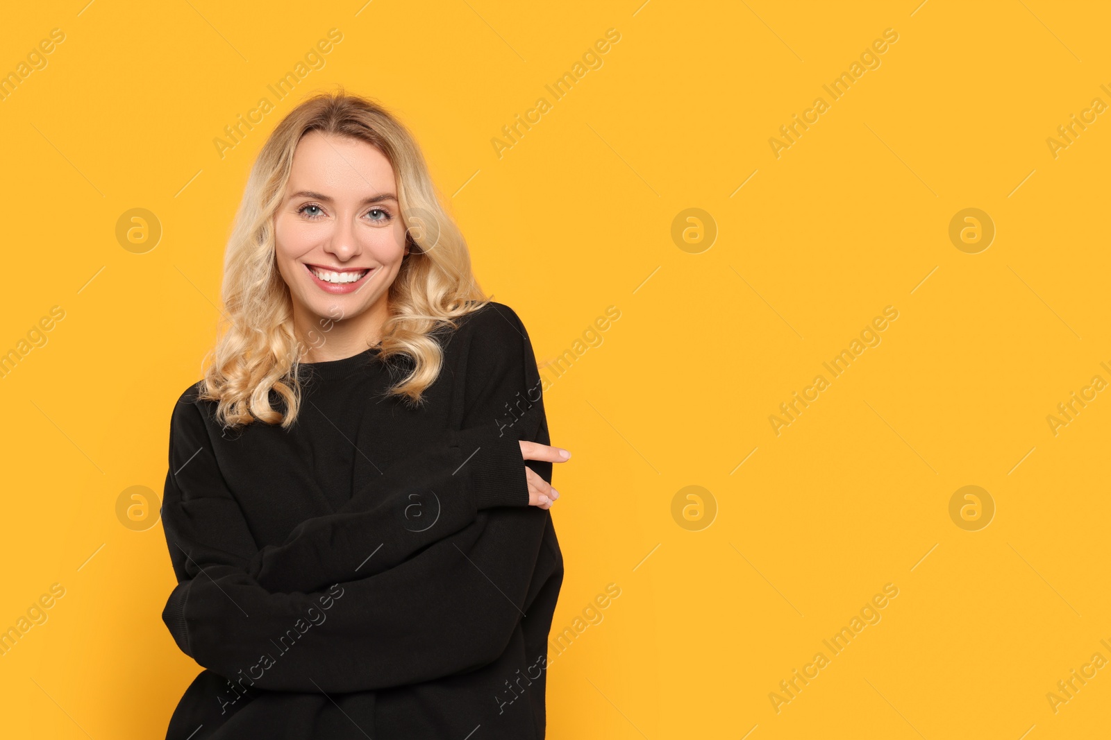 Photo of Happy woman in stylish warm sweater on orange background. Space for text