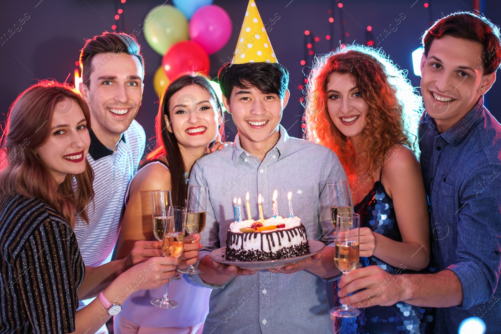 Photo of Young people celebrating birthday with cake in nightclub