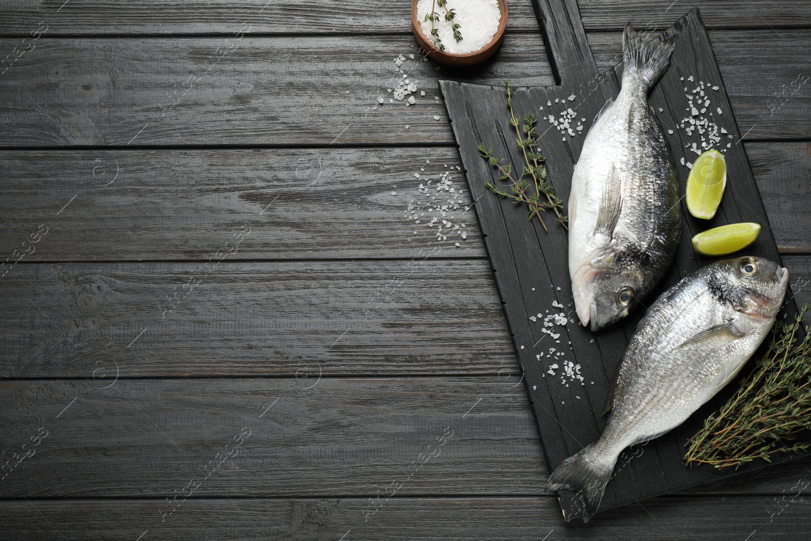 Photo of Raw dorada fish on black wooden table, flat lay. Space for text