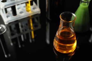 Photo of Laboratory glassware with different types of oil on black background, closeup