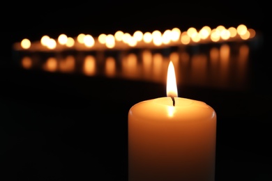 Small wax candle burning in darkness, closeup