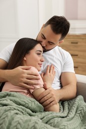 Photo of Affectionate young couple spending time together on sofa in living room