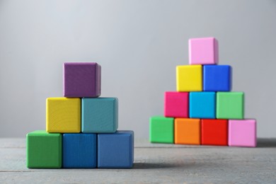 Photo of Pyramids of blank colorful wooden cubes against light grey background, selective focus