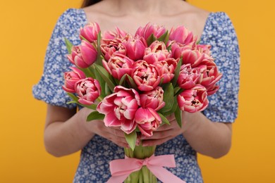 Photo of Woman with beautiful bouquet on orange background, closeup