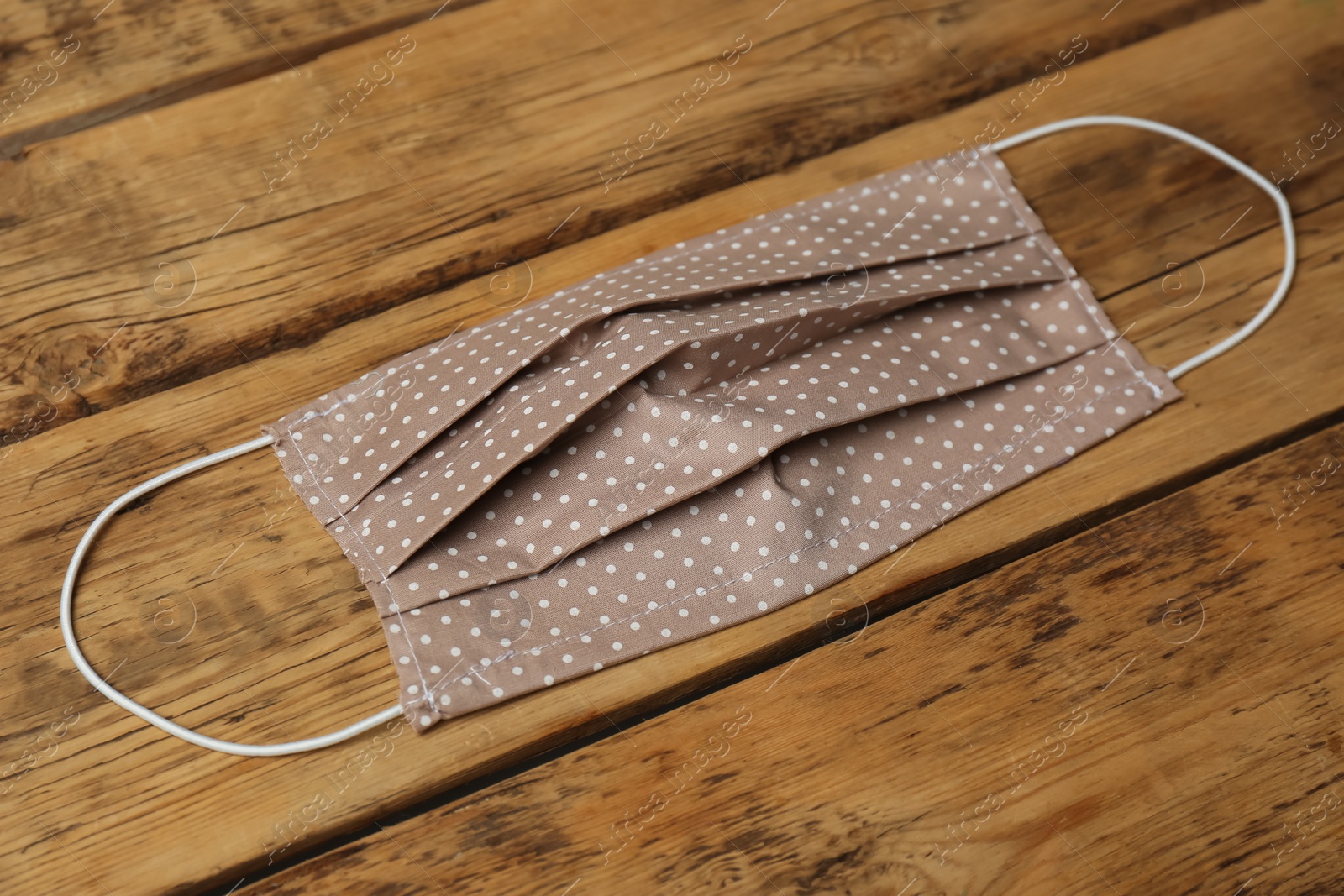 Photo of Homemade protective face mask on wooden table