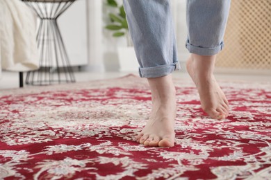 Photo of Woman standing on carpet with pattern at home, closeup. Space for text