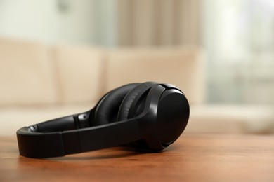 Photo of Modern wireless headphones on wooden table indoors, closeup