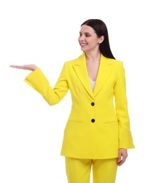 Beautiful businesswoman in yellow suit pointing at something on white background