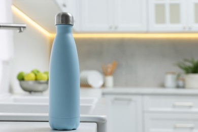 Photo of Stylish thermo bottle on white countertop in kitchen. Space for text