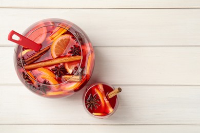 Photo of Glass and bowl of delicious aromatic punch drink on white wooden table, flat lay. Space for text