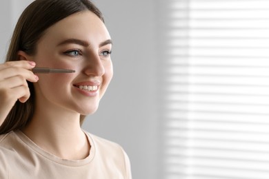 Photo of Smiling woman drawing freckles with pen indoors. Space for text