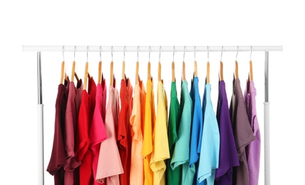 Photo of Many t-shirts hanging in order of rainbow colors on white background