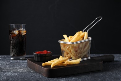 Photo of Tasty French fries, soda and ketchup on grey textured table