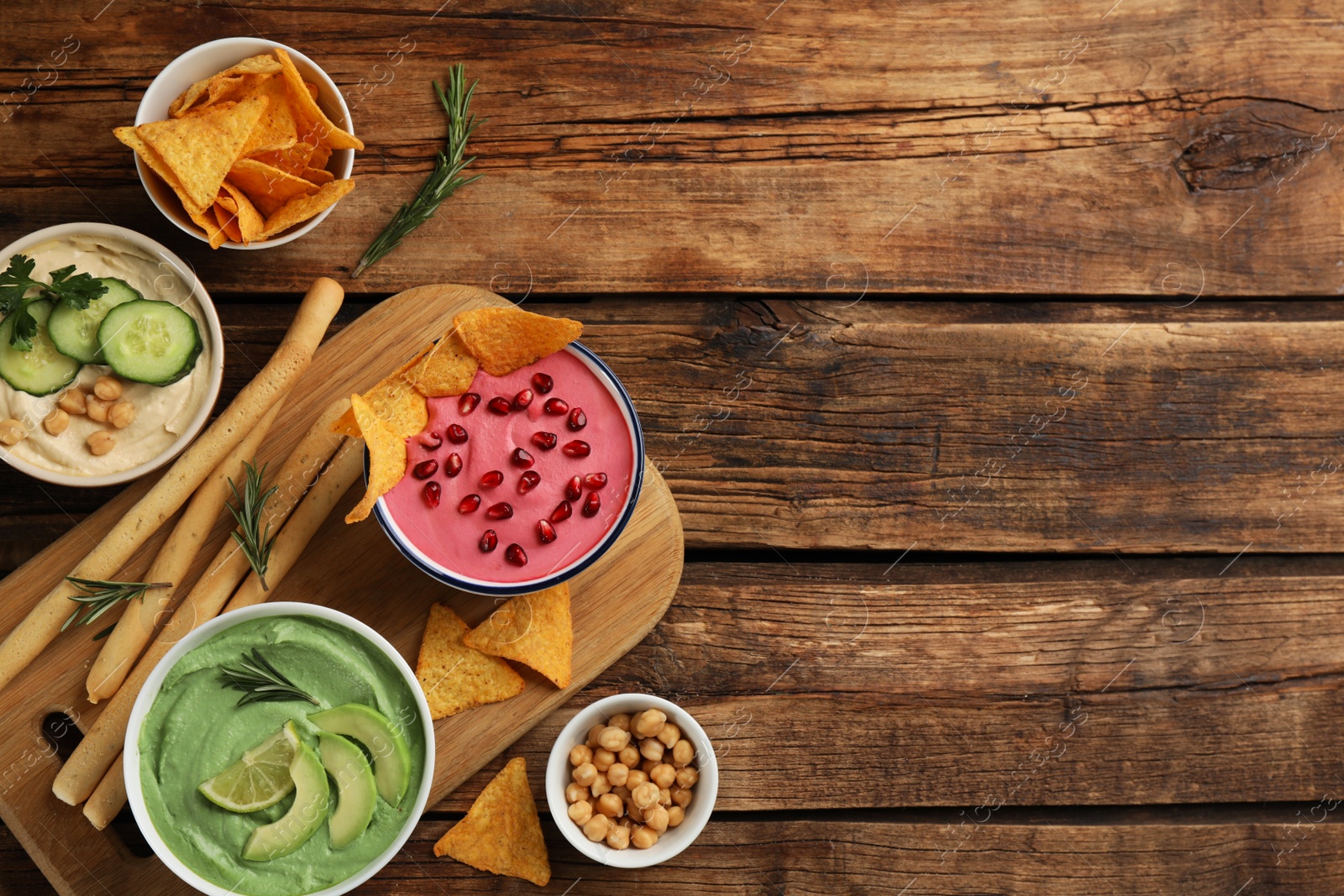 Photo of Flat lay composition with delicious hummuses on wooden table. Space for text