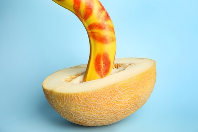 Photo of Fresh banana with red lipstick marks and melon on blue background. Sex concept