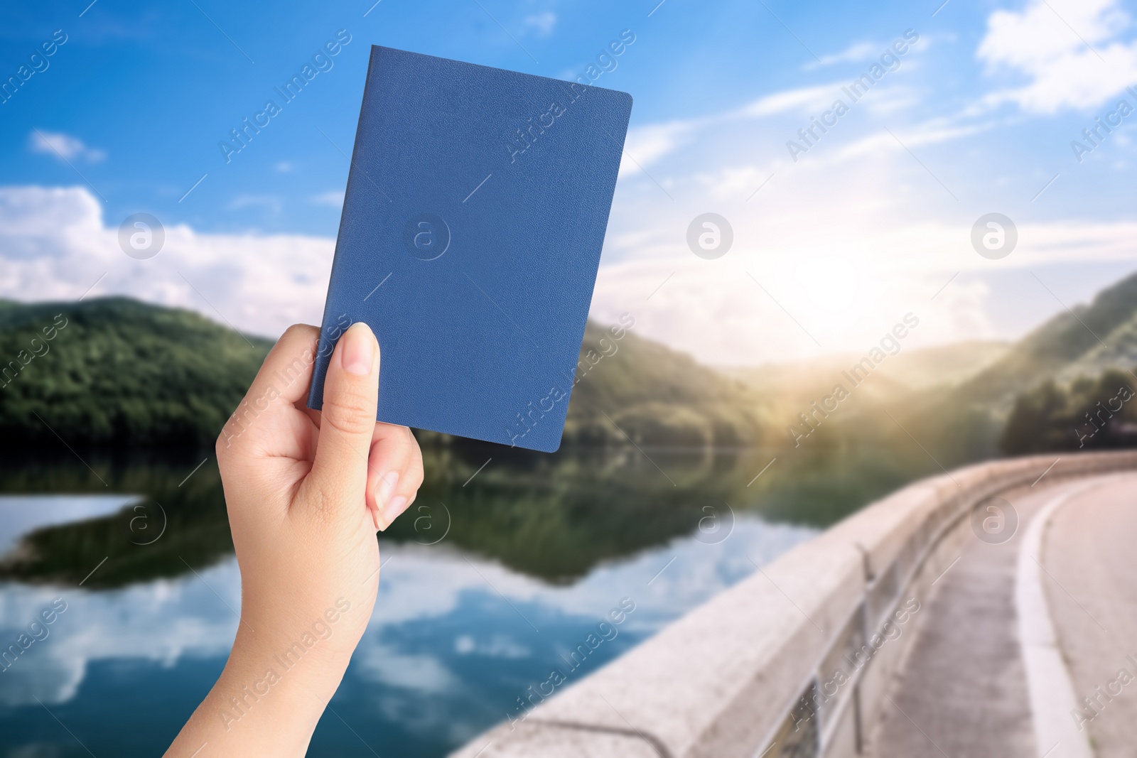 Image of Woman holding passport and beautiful view of road along lake on background