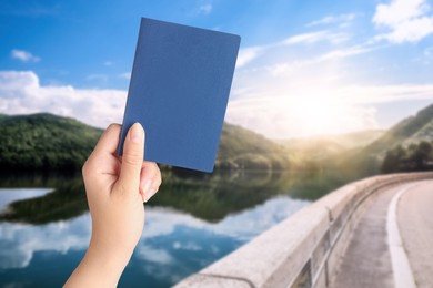 Image of Woman holding passport and beautiful view of road along lake on background