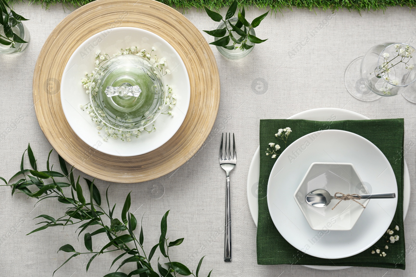 Photo of Elegant table setting with green plants on light cloth, flat lay