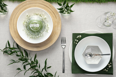 Photo of Elegant table setting with green plants on light cloth, flat lay