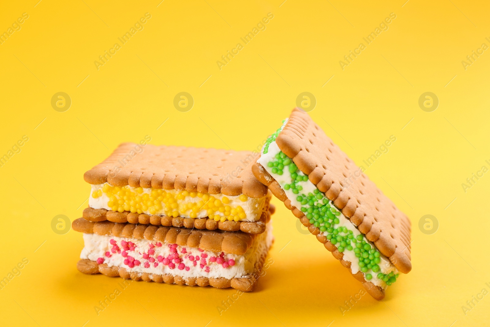 Photo of Sweet delicious ice cream cookie sandwiches on yellow background