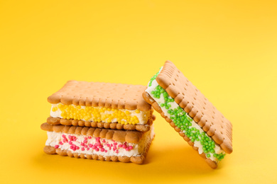 Sweet delicious ice cream cookie sandwiches on yellow background