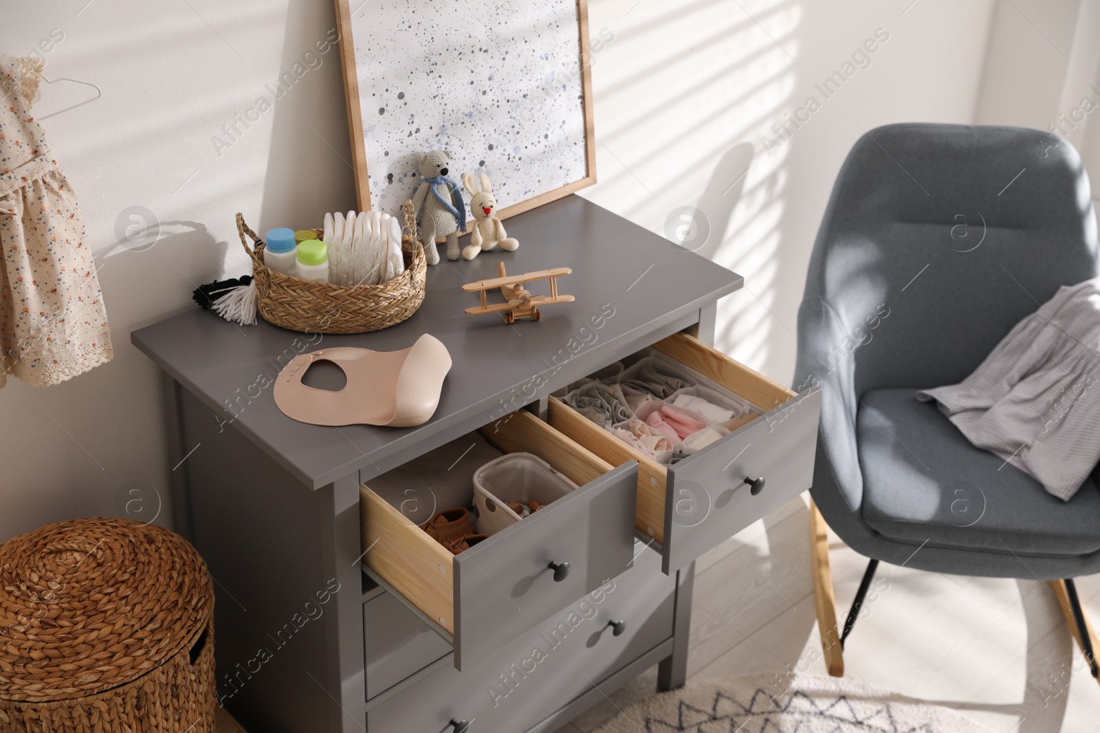 Photo of Open cabinet drawers with clothes and different items in child room