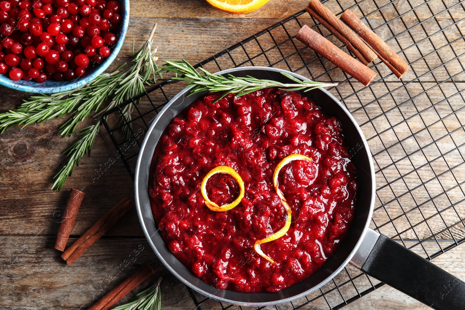 Photo of Flat lay composition with cranberry sauce in pan on wooden background