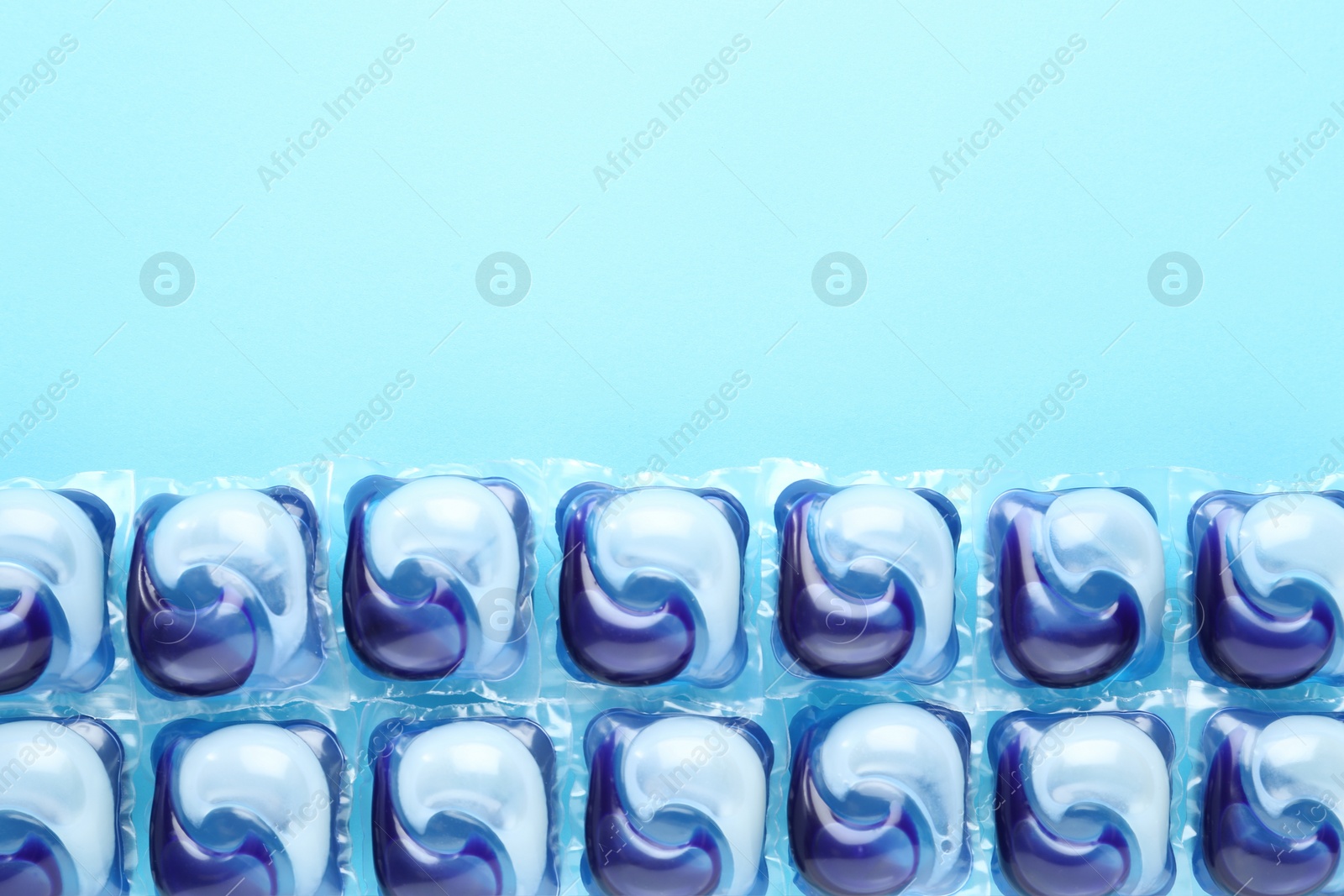 Photo of Laundry capsules on turquoise background, flat lay. Space for text