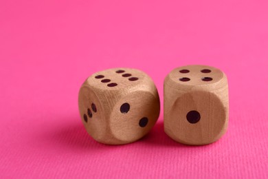 Two wooden game dices on pink background, closeup