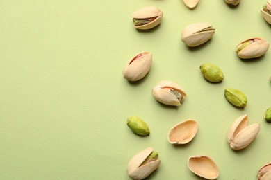 Photo of Organic pistachio nuts on color background, flat lay. Space for text
