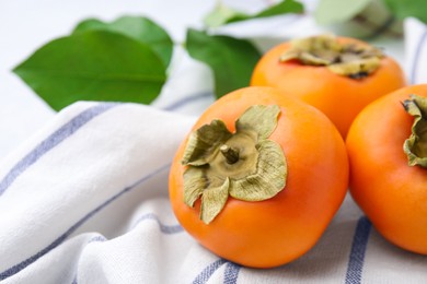 Delicious ripe juicy persimmons on striped cloth, closeup