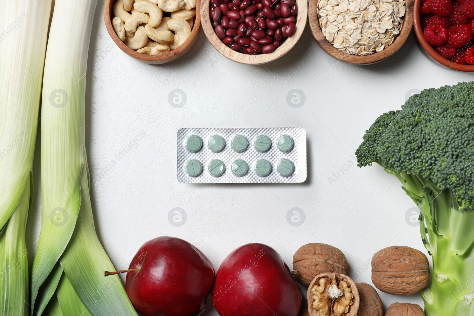 Photo of Blisters of pills and foodstuff on white table, flat lay. Prebiotic supplements