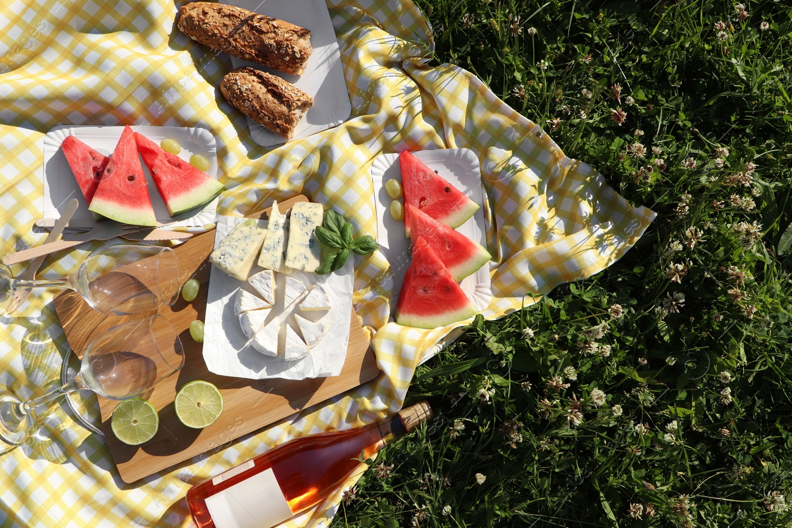 Photo of Picnic blanket with delicious food and wine on green grass outdoors, top view