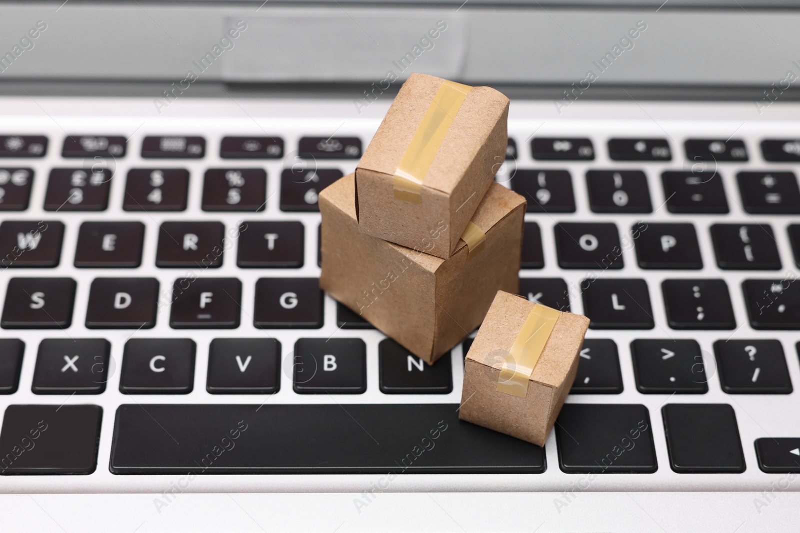 Photo of Internet shopping. Small cardboard boxes on laptop, closeup