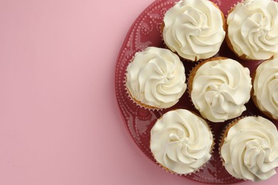 Photo of Tasty vanilla cupcakes with cream on pink background, top view. Space for text